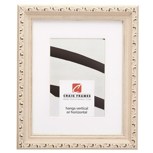 May include: A white picture frame with an ornate design. The frame is made of wood and has a cream finish. The frame is 8x10 inches and can be hung vertically or horizontally. The frame is made by Craig Frames.