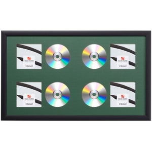 May include: Black picture frame with a green mat and six openings for displaying CDs. The frame is designed to hang vertically or horizontally. "Craig Frames" is printed on the mat.