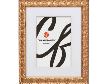 May include: Gold picture frame with an ornate design. The frame has a white mat and a clear opening for a photo or artwork. The frame is made by Craig Frames.