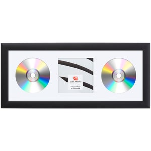 May include: Black picture frame with a white mat and two openings for CDs. The frame has a small label that reads "Craig Frames" and "Hangs vertical or horizontal".