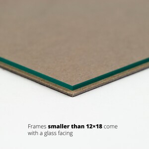 May include: Close-up of the edge of a picture frame showing a brown cardboard backing and a green glass facing. Text reads "Frames smaller than 12x18 come with a glass facing."