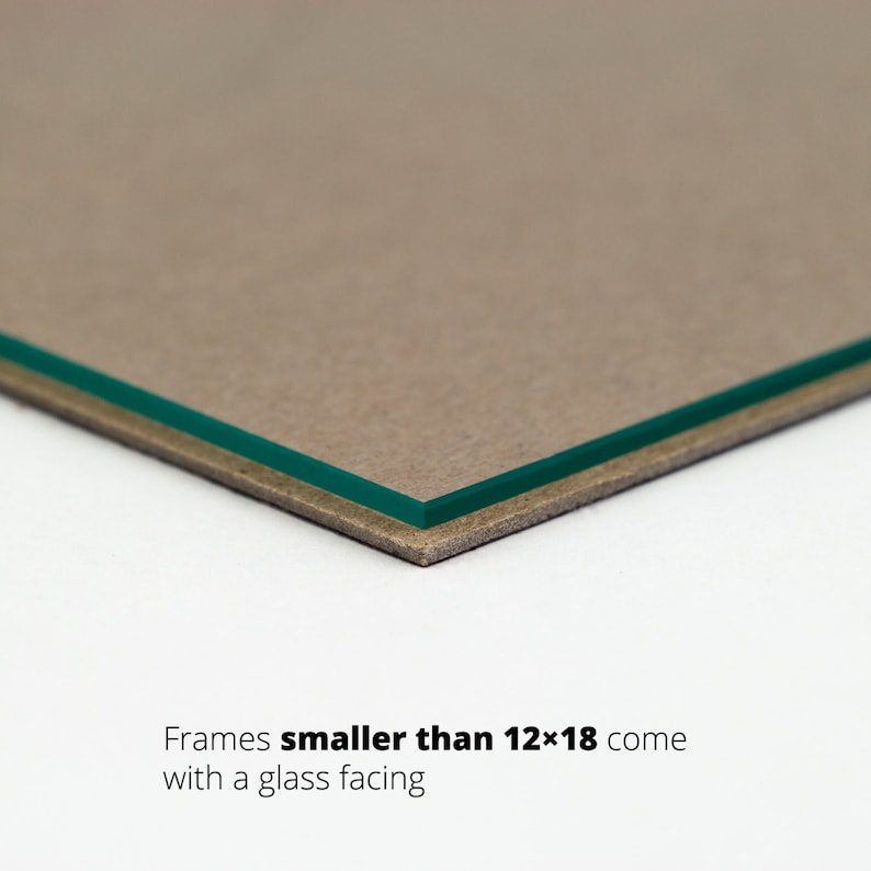 May include: Close-up of the edge of a picture frame showing a brown cardboard backing and a green glass facing. Text reads "Frames smaller than 12x18 come with a glass facing."