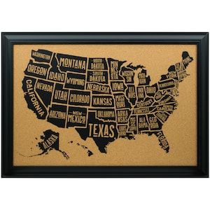 May include: A corkboard with a black frame and a map of the United States with each state labeled in gold lettering. The map is black and the background is cork.