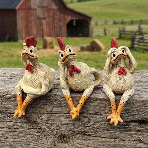 Może przedstawiać: Trzy fantazyjne figurki kurczaków z czerwonymi grzebieniami i kolczykami oraz żółtymi stopami z czarnymi kropkami. Kurczaki są w różnych pozach, siedząc na zwietrzałej drewnianej powierzchni, z oborą i polem w tle.