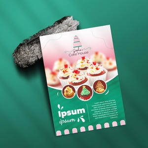 May include: A flyer for Sophia's Cake House, featuring cupcakes with white frosting and red heart sprinkles. The flyer has a pink and green gradient background with the text "Ipsum ipsum" and a logo. A piece of wood sits on the green surface.