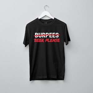 Peut inclure: Un t-shirt noir à manches courtes avec le texte blanc BURPEES barré d'une ligne rouge, placé au-dessus du texte rouge BEER PLEASE. Le t-shirt est présenté sur un cintre blanc sur un fond gris clair uni.