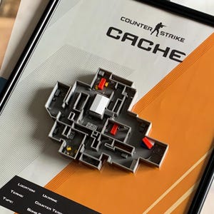 Könnte beinhalten: Gerahmtes Kunstwerk mit einem 3D-Modell der Cache-Karte aus Counter-Strike. Die Karte ist grau mit roten und gelben Akzenten, vor einem weißen und orangefarbenen Hintergrund. Der Rahmen ist schwarz, und das Kunstwerk enthält den Text "Counter-Strike" und "Cache".