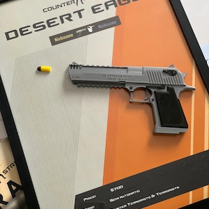 May include: Framed artwork featuring a Desert Eagle pistol with the text "Counter Strike" and "Desert Eagle." The artwork includes a bullet and details like "44 MAG" and "Made in USA."