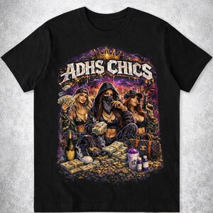 Könnte beinhalten: Schwarzes T-Shirt mit einer Grafik von drei Frauen, Geld und dem Text "ADHS CHICS". Die Illustration hat eine stilisierte Ästhetik, wobei eine Frau eine Waffe hält. Das Design integriert Elemente von Reichtum und urbanem Stil, mit einer Krone.