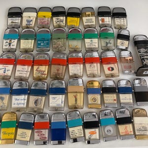 Könnte beinhalten: Eine Sammlung von Vintage-Feuerzeugen in verschiedenen Farben und Designs. Viele Feuerzeuge haben transparente Kunststoffkörper mit gedruckten Grafiken und Text. Einige haben Metallakzente und schwarze oder silberne Oberteile.