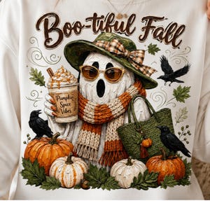 May include: A white sweatshirt featuring a graphic of a ghost wearing a green hat, sunglasses, and a striped scarf. The ghost holds a cup labeled Pumpkin Spice Vibes. The design includes three black crows, orange and white pumpkins, and green leaves.