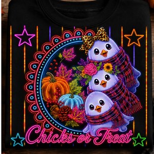 Può includere: Una t-shirt nera con una grafica in stile neon di tre pulcini fantasma che indossano sciarpe a quadri. Il design include una zucca, una zucca blu, foglie autunnali, fiori e un fiocco leopardato. Il testo "Chicks or Treat" è in basso.
