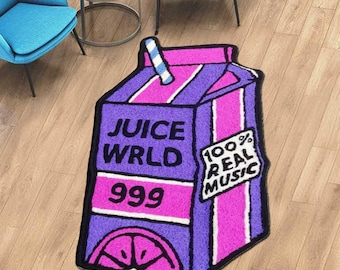 May include: A purple and pink Juice WRLD 999 rug shaped like a juice box, with the text "100% Real Music." Two blue chairs and a small round table are in the background. The rug is on a wooden floor.
