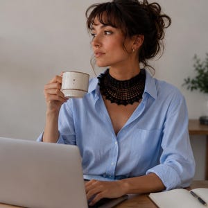 Può includere: Una camicia azzurra abbottonata abbinata a una collana con colletto all'uncinetto nero. La camicia presenta un colletto classico e maniche lunghe. La collana nera ha un motivo traforato dettagliato e complesso che riposa attorno al collo.