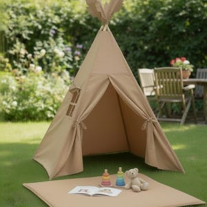 Può includere: Una tenda tipi in tessuto beige con una parte superiore a punta, dotata di una finestra laterale e lembi frontali legabili. Un tappetino beige abbinato è posizionato davanti, con due piccoli giocattoli impilabili colorati, un orsacchiotto e un libro aperto.