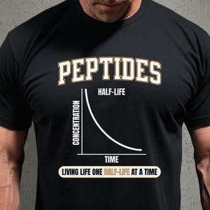 May include: Black t-shirt with the word "PEPTIDES" in a white and gold collegiate font. Below the word "PEPTIDES" is the text "HALF-LIFE". A graph shows concentration over time. The phrase "LIVING LIFE ONE HALF-LIFE AT A TIME" is at the bottom.