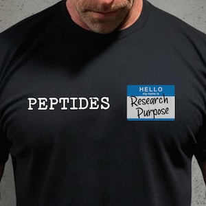 May include: Black t-shirt with the word "PEPTIDES" in white block letters. A blue name tag graphic reads "HELLO my name is Research Purpose". The shirt is made of a dark, solid material.