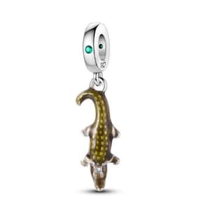 Può includere: Un charm in argento con una gemma verde e un ciondolo a forma di alligatore verde oliva e marrone. Il charm alligatore è un ciondolo con un design strutturato, perfetto per un braccialetto o una collana.