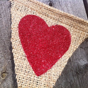 May include: A burlap banner with a red glitter heart. The banner is perfect for a Valentine's Day party or wedding.