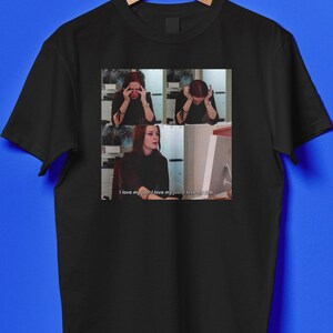 May include: Black t-shirt featuring a meme with three panels. The top two panels show a person with their hands on their head. The bottom panel shows the person looking at a computer. The text "I love my job. I love my job. I love my job." is below.