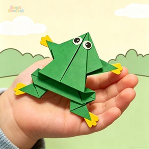 May include: A green origami frog with yellow feet and googly eyes. The frog is made of folded paper and is in a jumping pose. The background is a light yellow with a cartoon-style landscape.