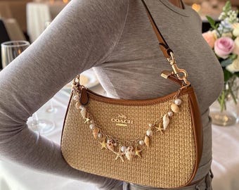 Bolso de hombro tejido beige vintage de los años 90 con dije de concha de perla, estilo bohemio costero.