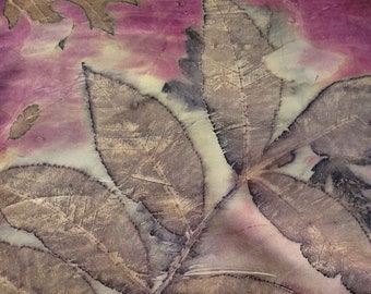 May include: A pink silk scarf with a brown leaf print. The leaves are arranged in a pattern that resembles a branch. The scarf is folded and draped over a surface.