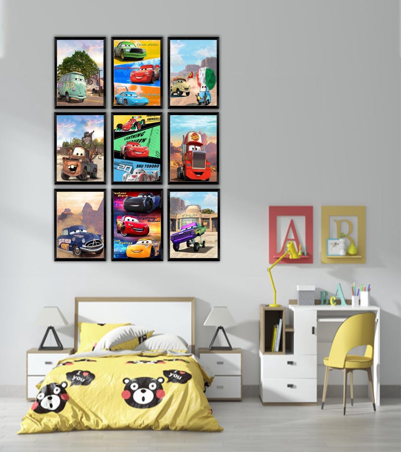 Puede incluir: Una colecci&oacute;n de nueve l&aacute;minas de arte mural rectangulares y enmarcadas que presentan varios personajes de coches animados de la franquicia Cars, dispuestas en una cuadr&iacute;cula de tres por tres en una pared lisa sobre una cama con edred&oacute;n amarillo.