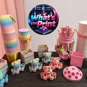 May include: A display of 3D-printed objects in pastel shades, such as bear figures, boxes, and cylindrical holders. The items are arranged on a dark surface, with a logo that says "What's the Print" in the background.