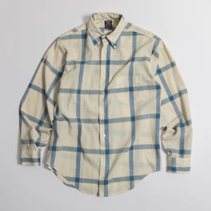 May include: A long-sleeve button-down shirt in a cream color featuring a large blue and tan plaid pattern. The shirt includes a pointed collar, a single chest pocket on the left side, and white buttons running down the center front placket.