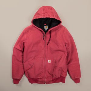May include: A red hooded jacket with a full-length front zipper, long sleeves, and ribbed cuffs. The jacket features a black interior lining, a drawstring hood, and a front kangaroo pocket with a Carhartt brand label stitched on the front.