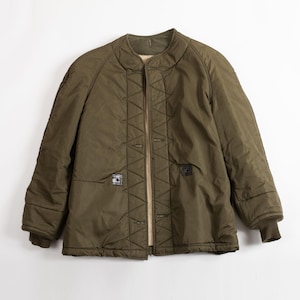 May include: Olive green quilted jacket with a round collar and button closure. The jacket features two front pockets and ribbed cuffs. The interior lining is a light tan color. A vintage style jacket.