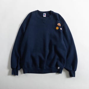 May include: Navy blue sweatshirt with a crew neck and long sleeves. The sweatshirt features embroidered sports ball graphics, including a football, baseball, and a basketball. The brand logo is visible on the upper left chest.