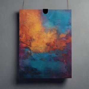 Puede incluir: Impresión artística abstracta con un diseño texturizado y colorido. La obra de arte muestra una mezcla de tonos naranja, turquesa, morado y azul, creando una composición vibrante y dinámica. La impresión es rectangular y cuelga de una cuerda sobre un fondo gris.
