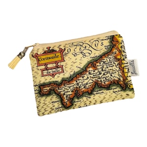 May include: A rectangular pouch with a map of Cornwall printed on it. The pouch has a beige background with a detailed map in shades of brown and gold. The word "Cornwaile" is printed on the pouch. A gold zipper and tassel complete the design.