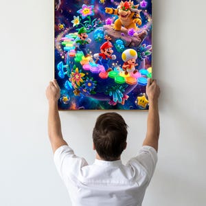 May include: A framed print featuring a vibrant scene from a video game. The artwork depicts characters on a colorful path with a cosmic background. The print is held up by a person.