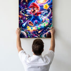 May include: A framed art print featuring a vibrant illustration of Mario in a space-themed setting. Mario, in his signature red cap and blue overalls, is depicted running across a colorful path. The background showcases a galaxy with planets, stars, and a yellow star.
