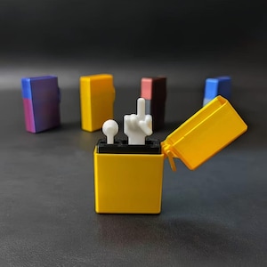 May include: A yellow lighter with a white hand giving the middle finger. The lighter's lid is open, revealing the hand gesture. Other lighters in various colors are in the background.