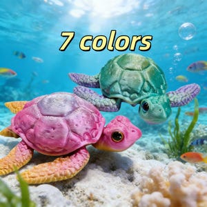 May include: Two colorful turtle figurines in an underwater scene. One is pink and yellow, the other is green and purple. The text "7 colors" is above them. The turtles have large eyes and are surrounded by fish and bubbles.