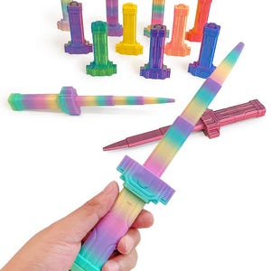 May include: A 3D-printed, multi-coloured telescopic sword with a rainbow gradient design. The image shows several toy swords and their bases in various colours, including green, yellow, purple, and orange. The text at the top reads "3D PRINTER ARMOR TELESCOPIC SWORD."