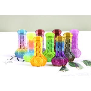 May include: A selection of vibrantly coloured bottle stoppers with a futuristic design. The stoppers feature a range of colours, including blue, green, yellow, purple, and gold. Each stopper has a geometric shape with a broad base and a slender top.