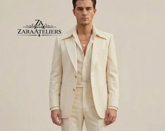 May include: A cream-colored suit with a matching shirt and pants. The suit has a two-button closure and a notched lapel. The shirt is open at the collar, and a gold necklace is visible. The text "ZARAATELIERS" is in the upper left corner.