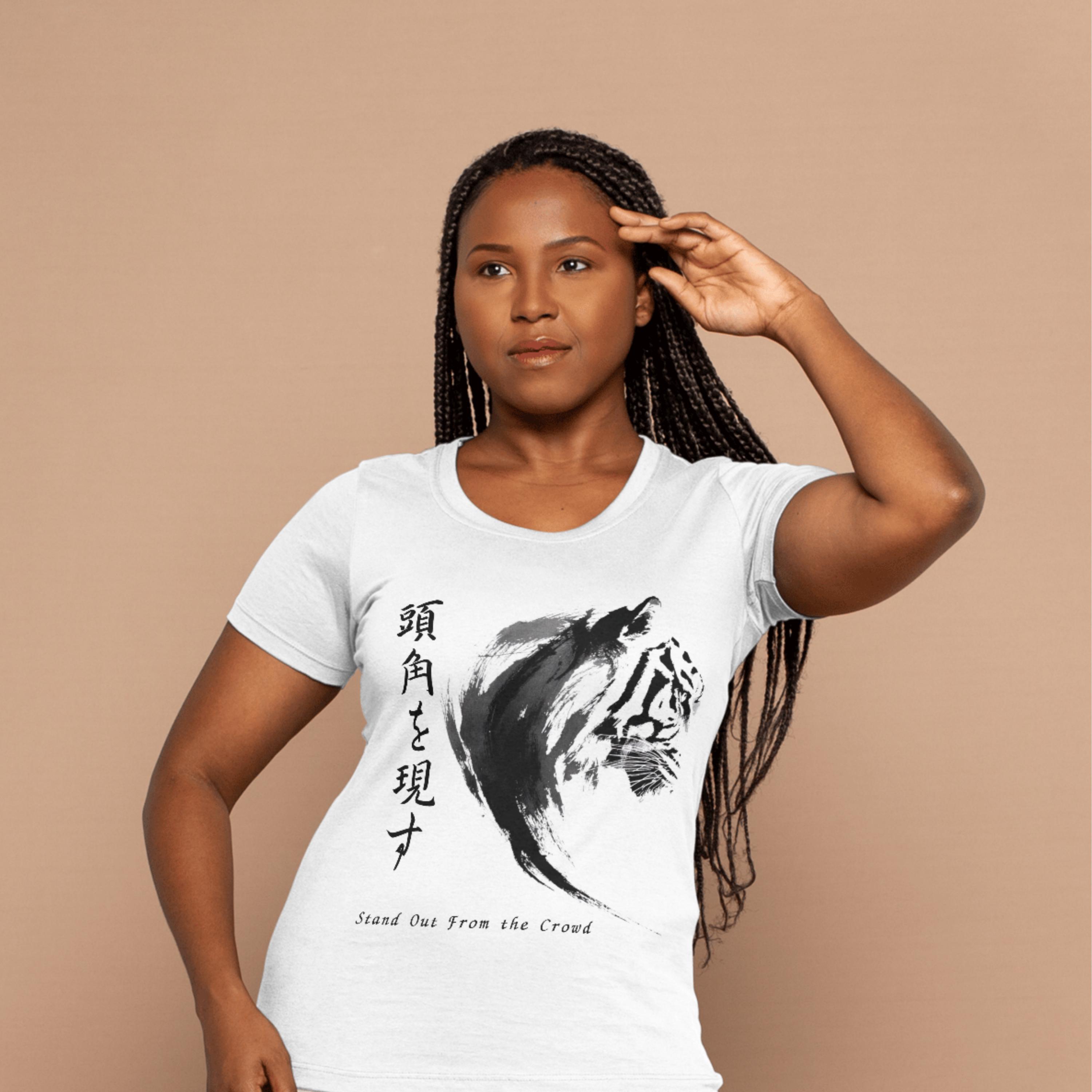 Peut inclure: T-shirt blanc avec une illustration de tigre noir et blanc et du texte japonais. Le design comprend la phrase « Démarquez-vous de la foule ». Le tigre est représenté dans un style coup de pinceau.