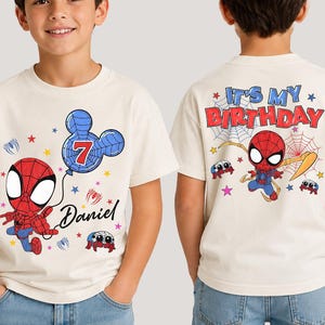 May include: A cream-colored short-sleeve t-shirt featuring a graphic of a red and blue superhero character holding a balloon shaped like a mouse head with the number 7 and the name Daniel. The back displays the text IT'S MY BIRTHDAY.