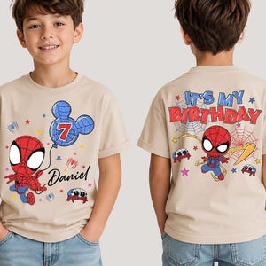May include: A beige short-sleeve t-shirt featuring a Spider-Man graphic. The front displays a cartoon Spider-Man holding a Mickey-shaped balloon with the number 7 and the name Daniel. The back features Spider-Man with the text IT'S MY BIRTHDAY.
