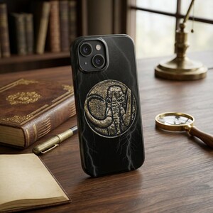 May include: Black iPhone case with a gold-colored mammoth design. The case has a marble-like texture with lightning bolt accents. The mammoth is in a circular emblem. The case is on a wooden surface.