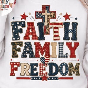 Puede incluir: Sudadera blanca con las palabras "FAITH FAMILY FREEDOM" en un diseño patriótico. Las letras presentan patrones de estrellas, rayas y camuflaje. También se incluye una cruz y estrellas.