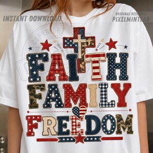 Puede incluir: Una camiseta blanca de manga corta con un diseño gráfico que incluye el texto FAITH FAMILY FREEDOM. Las letras y una cruz central están rellenas con varios patrones, incluyendo estrellas de la bandera estadounidense, cuadros rojos y camuflaje.