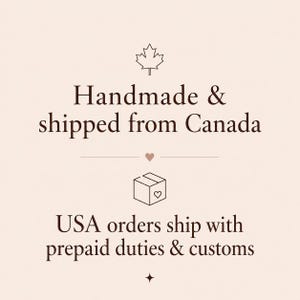 Pode incluir: Um gr&aacute;fico bege claro com texto em castanho escuro que diz: Handmade & shipped from Canada, seguido por um pequeno cora&ccedil;&atilde;o, um &iacute;cone de caixa com um cora&ccedil;&atilde;o e o texto: USA orders ship with prepaid duties & customs. Inclui um &iacute;cone de folha de &aacute;cer.