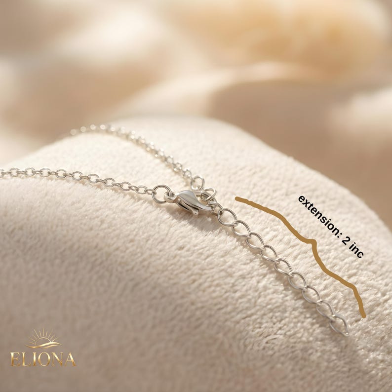 May include: Close-up of a silver necklace with a chain and clasp. The necklace has an extension of 2 inches. The brand name "ELIONA" is visible at the bottom left.